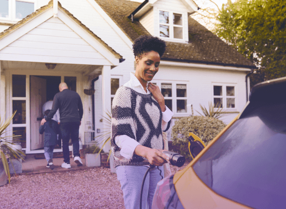 Woman charging an electric vehicle in front of her house.